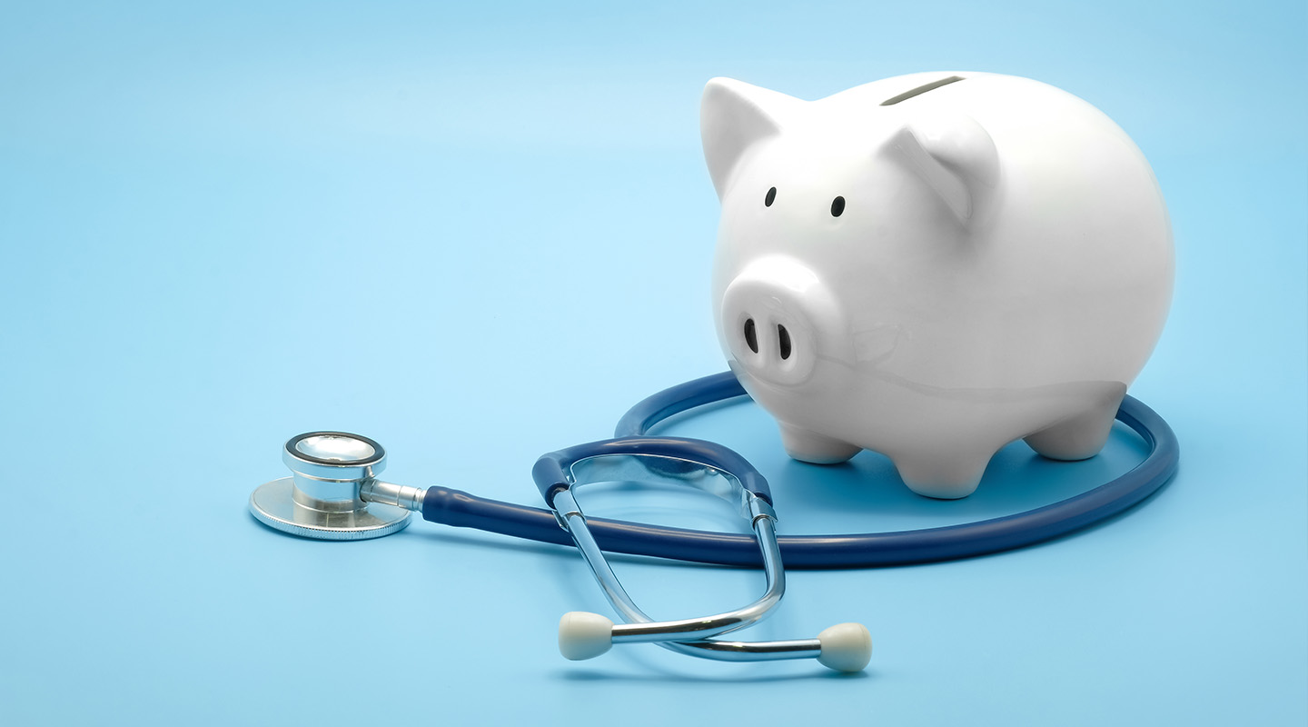 A piggy bank sits on top of a stethoscope.