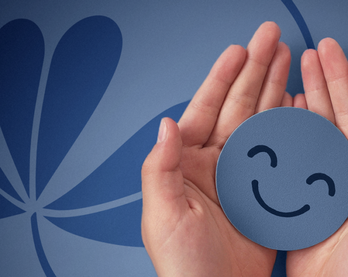 Hands holding a digital smiley face above a Notre Dame FCU shamrock logo.