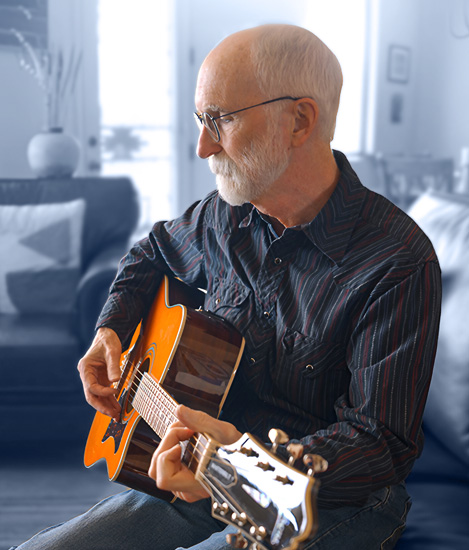 Hombre tocando una guitarra en un sofá. Fondo estilizado en azul con ondas de sonidos blancos provenientes del hombre.