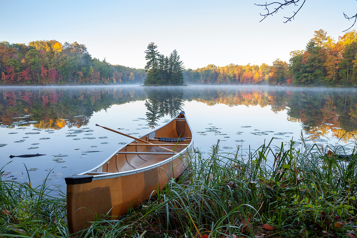 Yellow canoe on the shore of a beautiful lake with an island in northern Minnesota at dawn
