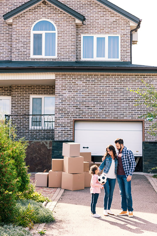 young family standing together in front of new house
